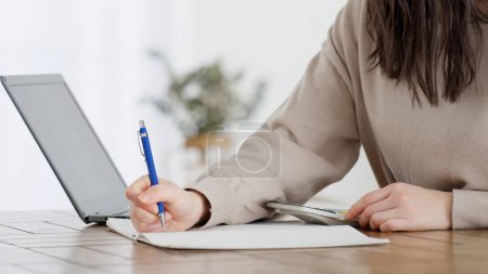 A woman calculating with a calculator and taking notes