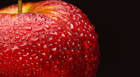 manzana roja madura con gotas sobre fondo negro