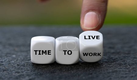 Photo for Hand turns dice and changes the expression 'time to work' to 'time to live'. - Royalty Free Image