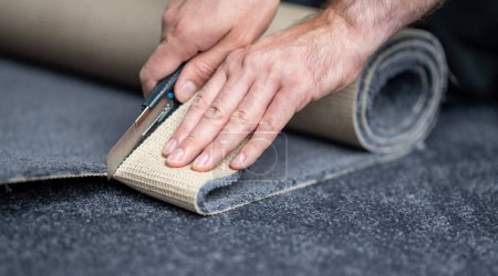 Handyman cutting a new carpet with a carpet cutter..	