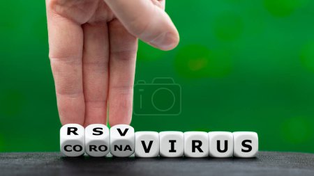 Foto de La mano gira los dados y cambia la expresión 'virus corona' a 'virus RSV'. - Imagen libre de derechos