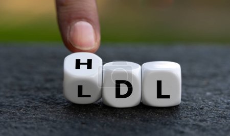 Hand turns dice and changes the abbreviation LDL (low-density lipoprotein) to HDL (high-density lipoprotein).