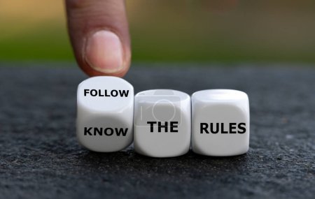 Foto de Hand turns dice and changes the expression 'know the rules'. to 'follow the rules'. - Imagen libre de derechos
