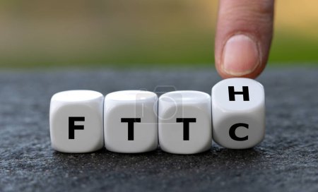 Photo for Hand turns dice and changes the expression Fiber to the curb (FTTC) to Fiber to the home (FTTH). Symbol for connecting residences directly with optical fibers. - Royalty Free Image