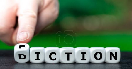 Photo for Hand turns dice and changes the word diction to fiction. - Royalty Free Image