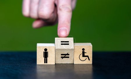 Foto de Símbolo para la igualdad de derechos de las personas con discapacidad. La mano gira cubo de madera y cambia el signo desigual a un signo igual. - Imagen libre de derechos