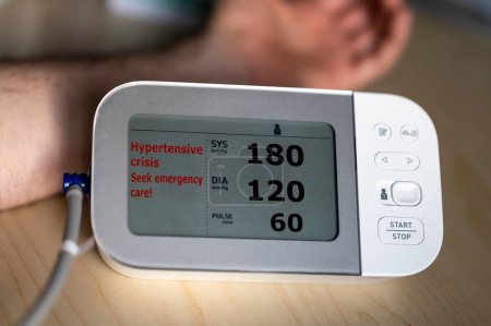 Monitor de presión arterial indica valores altos que están en la categoría 'crisis hipertensiva'.