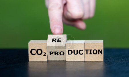 Hand dreht Holzwürfel und ändert den Ausdruck "CO2-Produktion" in "CO2-Reduktion".