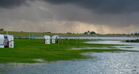 Photo for Beach chairs at the beach of Altenbruch near Cuxhaven in Germany. Beach flooded after a summer storm. - Royalty Free Image