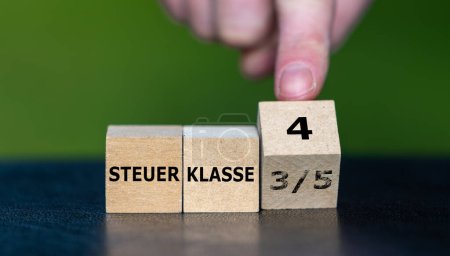 Symbol for the change of tax class 3/5 to 4 in Germany. Hand turns cube and changes the German expression 'Steuerklasse 3/5' (tax class 3/5) to 'Steuerklasse 4' (tax class 4).-stock-photo
