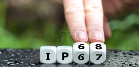 Photo for Hand is turning dice and changes the expression 'IP67' to 'IP68' as symbol for a higher water resistance class. - Royalty Free Image