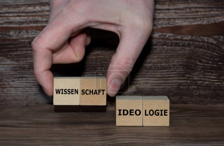 Photo for Hand picks cubes with the German word 'Wissenschaft' (science) instead of 'Ideologie' (ideology). - Royalty Free Image