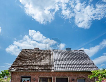 Foto de A half cleaned house roof shows the before and after effect of a roof cleaning. - Imagen libre de derechos