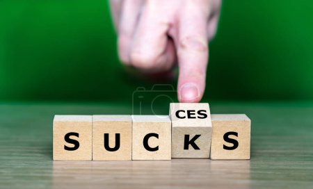 Photo for Hand turns wooden cube and changes the word sucks to success. - Royalty Free Image