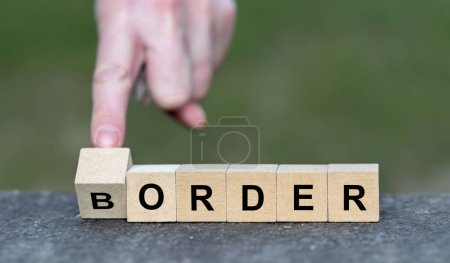 Hand turns wooden cube and changes the word border to order. Symbol for strict border control.
