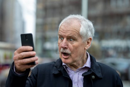 Senior man loocking in shock at his mobile phone.