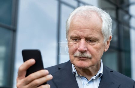 Senior Business man in a suit looking concentrated at his mobile phone 