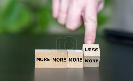 Hand dreht Würfel und ändert den Ausdruck "mehr, mehr, mehr" in "mehr, mehr, mehr, weniger". Symbol dafür, den Wunsch aufzuhalten, immer mehr von etwas haben zu wollen.