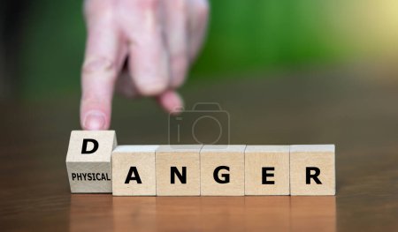 Hand dreht Holzwürfel um und ändert den Ausdruck "körperliche Wut" in "gefährlich".