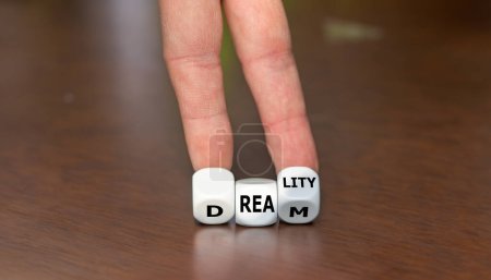Hand turns dice and changes the word dream to reality.