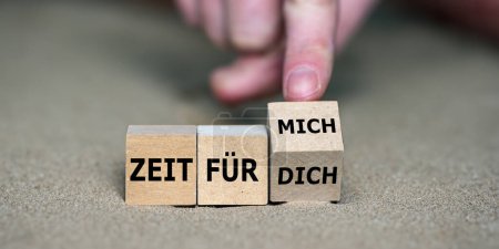Hand turns cube and changes the German expression 'zeit fr dich' (time for you) to 'zeit fuer mich' (time fo myself).