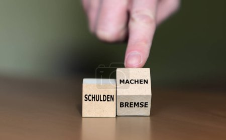 Hand dreht Würfel und ändert den deutschen Ausdruck "Schuldenbremse" in "Schulden machen").