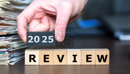 Holzwürfel bilden neben einem Papierstapel den Ausdruck "2025 Review".