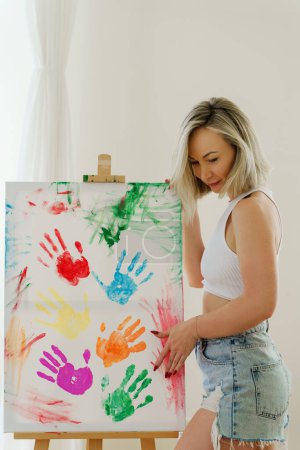 Foto de Mujer joven dibujando con sus palmas usando colores coloridos del arco iris creando obras de arte modernas para apoyar a la comunidad LGBT - Imagen libre de derechos