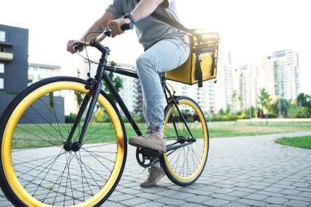 Téléchargez les photos : Express livreur de nourriture est sur un vélo avec un sac isolé derrière son dos. - en image libre de droit