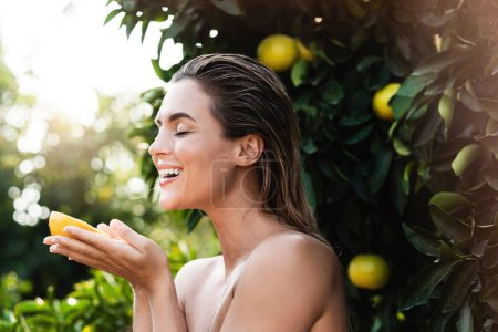 Foto de Retrato al aire libre de mujer hermosa con la piel lisa con una fruta de limón en sus manos - Imagen libre de derechos