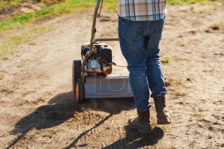 Photo for Closeup shoot of man using aerator machine to scarification and aeration of lawn or meadow - Royalty Free Image