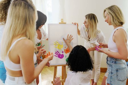 Photo for Group of young women drawing with their palms using colorful rainbow colors creating modern artwork to support LGBT community - Royalty Free Image