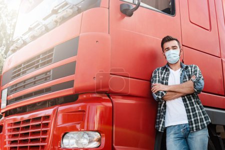 Téléchargez les photos : Jeune conducteur de camion portant un masque de protection en raison de la pandémie de virus - en image libre de droit