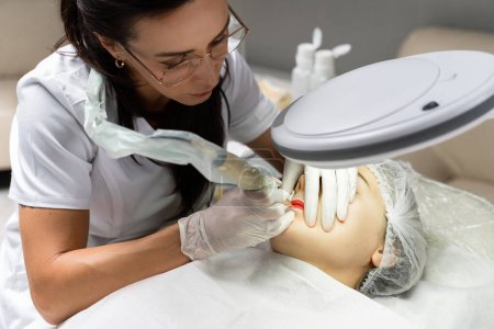 Foto de Artista de maquillaje permanente profesional y su cliente durante el procedimiento de rubor labial - Imagen libre de derechos