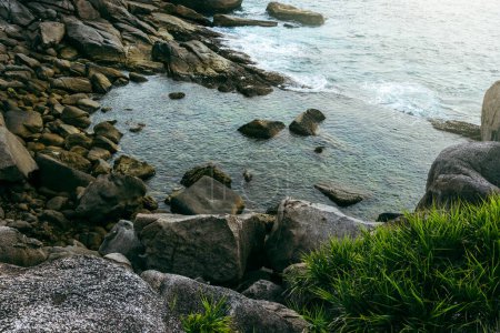 Téléchargez les photos : Vagues mousseuses s'écrasant sur une côte insulaire rocheuse et désolée pendant une marée haute. - en image libre de droit