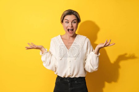 Photo for Young blond woman making silly face against yellow background - Royalty Free Image