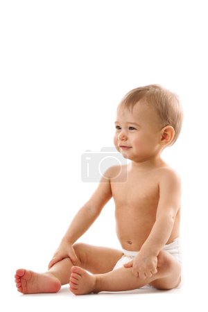 Téléchargez les photos : Adorable petit garçon en bonne santé dans la couche est assis et souriant sur fond blanc. - en image libre de droit