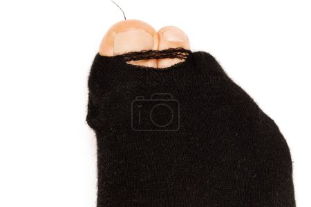 Photo for Closeup shot of a black holey sock on a male foot with toes sticking out on white background. Concept of poverty and financial crisis. - Royalty Free Image