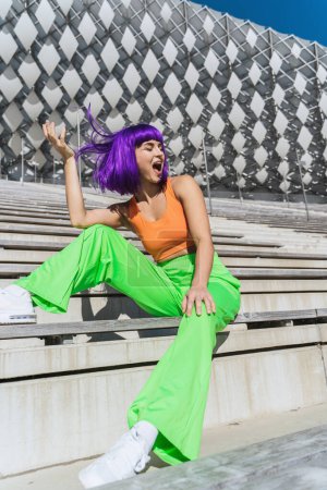 Téléchargez les photos : Femme insouciante et heureuse portant des vêtements de sport colorés dans la rue pendant la journée d'été - en image libre de droit