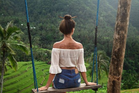 Young woman on rope swings with beautiful view on rice terraces in the Bali.
