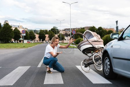 Photo for Horrified mother on the crosswalk after a car accident when a vehicle hits her baby pram. Concepts of safety, traffic code and insurance. - Royalty Free Image