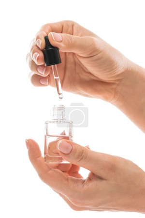 Foto de Manos femeninas y botella de aceite nutritivo de cutícula con un gotero sobre fondo blanco - Imagen libre de derechos