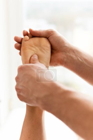 Téléchargez les photos : Masseur homme pendant le traitement de médecine intégrative massage des pieds féminin - en image libre de droit