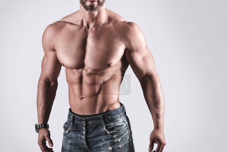 Photo for Muscular man bodybuilder wearing jeans posing against gray background - Royalty Free Image