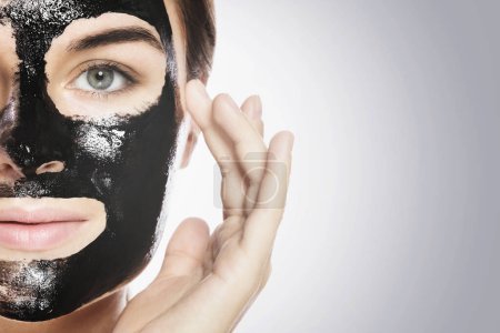 Téléchargez les photos : Jeune femme avec un masque noir nettoyant en profondeur sur son visage - en image libre de droit