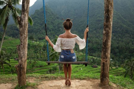 Téléchargez les photos : Jeune femme sur corde balançant avec une belle vue sur les terrasses de riz à Bali. - en image libre de droit