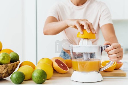 Photo for Closeup of female hands and citrus juicer during fresh orange juice preparation - Royalty Free Image
