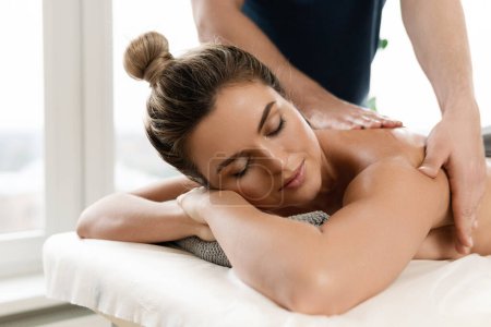 Téléchargez les photos : Masseur homme faisant massage du dos pour son client dans une clinique de massage professionnelle - en image libre de droit