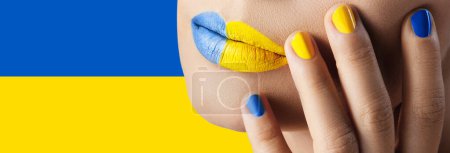 Foto de Primer plano de labios femeninos con lápiz labial amarillo y azul y bandera de Ucrania en el fondo - Imagen libre de derechos