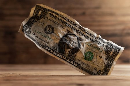 Foto de Primer plano de un billete arrugado de un dólar atascado en un hueco en el suelo. - Imagen libre de derechos